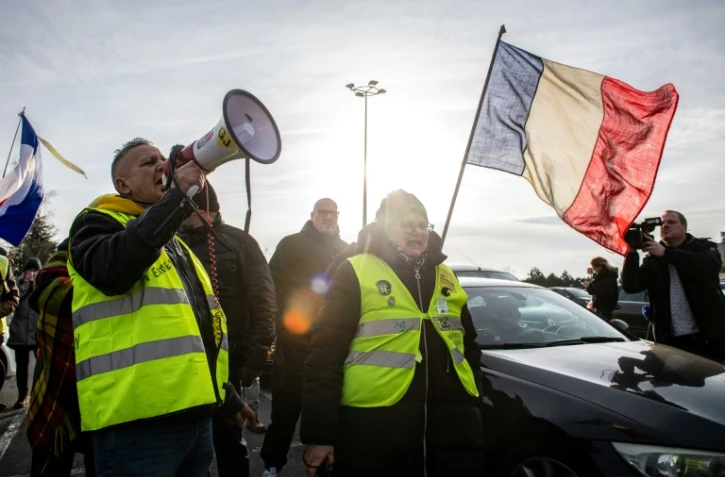Des participants à des convois anti-pass, portant des gilets jaunes, agitent des drapeaux sur une route dans le nord de la France, le 13 février 2022
