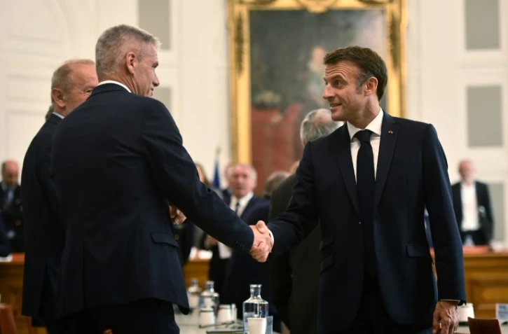 Le président français Emmanuel Macron (d) salue des élus locaux durant une visite à Pau, le 6 juillet 2023