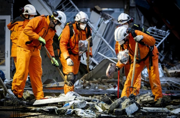 Des pompiers sur le site de l'effondrement d'un immeuble résidentiel après une explosion et un incendie, le 7 décembre 2024 à La Haye, aux Pays-Bas