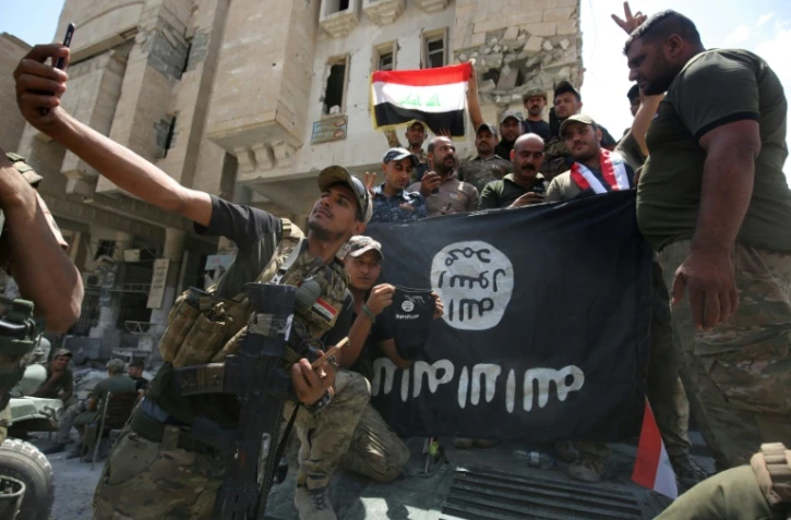 Des membres des forces de sécurité irakiennes posent autour d'un drapeau à l'envers de l'Etat islamique, le 8 juillet 2017 à Mossoul