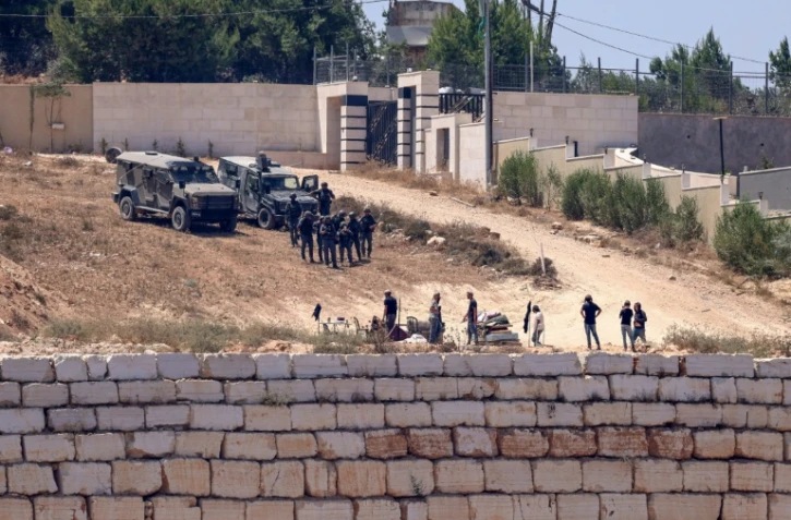 Des soldats israéliens au dessus de colons à Des soldats israéliens (en haut) montent la garde aux côtés de colons devant des maisons palestiniennes dans le village de Qusra, au sud de Naplouse, en Cisjordanie occupée, le 12 août 2026