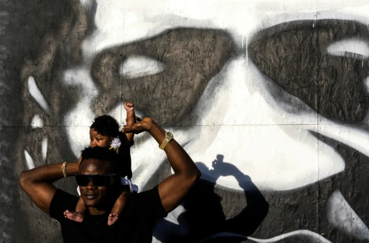 Un Américain lève le poigt de sa fille devant le mémorial improvisé en l'honneur de George Floyd, à Minneapolis le 25 mai 2021