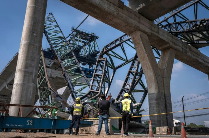 Des secouristes interviennent sur le site où une grue de chantier s'est effondrée sur une autoroute à Samut Sakhon, dans la banlieue de Bangkok, le 15 janvier 2026