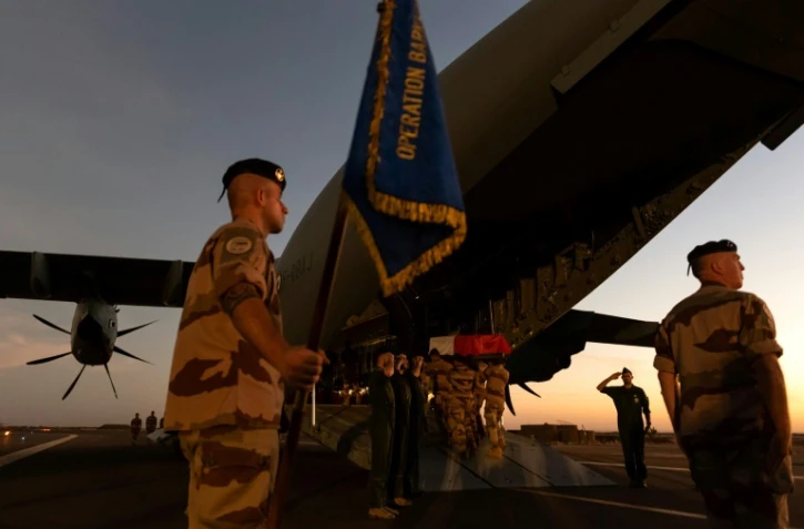 Les cercueils recouverts du drapeau aux couleurs de la France, près d'un soldat brandissant un étendard portant la mention "Opération Barkhane", avant d'être embarqués dans le gros porteur. Photo prise le 30 novembre 2019 et fournie le 1er décembre 2019 par le service de presse des armées Sirpa