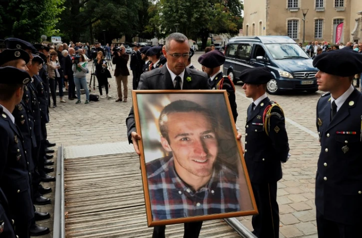 Un employé des services funéraires passe entre des soldats du 13e bataillon de chasseurs alpins de Chambéry avec un portrait d'Arthur Noyer, sur le parvis de la cathédrale Saint-Etienne à Bourges, le 7 septembre 2018, jour de ses funérailles