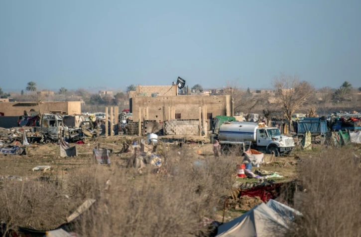 Le drapeau noir de l'organisation Etat islamique (EI) flotte au dessus d'un bâtiement dans la dernière poche de l'EI dans le village de Baghouz en Syrie, le 9 mars 2019