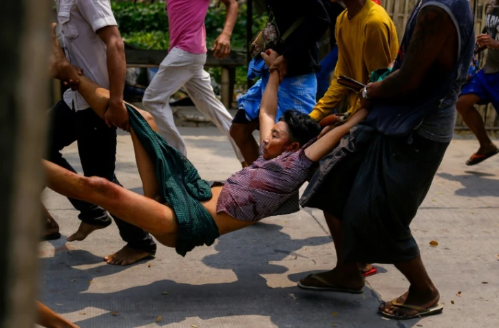 Transport d'un blessé lors des affrontements entre forces de l'ordre et manifestants dans la commune de Hlaing Tharyar, dans l'agglomération de Rangoun, le 14 mars 2021
