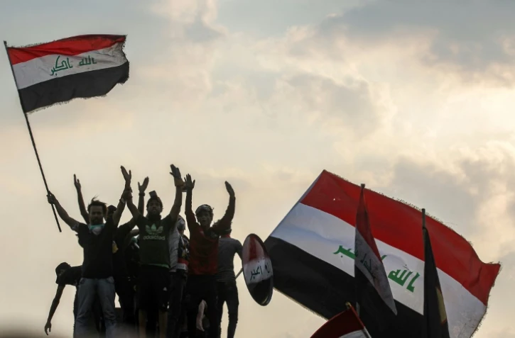 Des Irakiens agitent le drapeau national lors de manifestations dans le centre-ville de Bagdad, le 29 octobre 2019