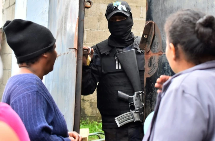 Des parents de détenus demandent des nouvelles de leurs proches à un policier devant la prison de Tela après des affrontements meurtriers, le 21 décembre 2019
