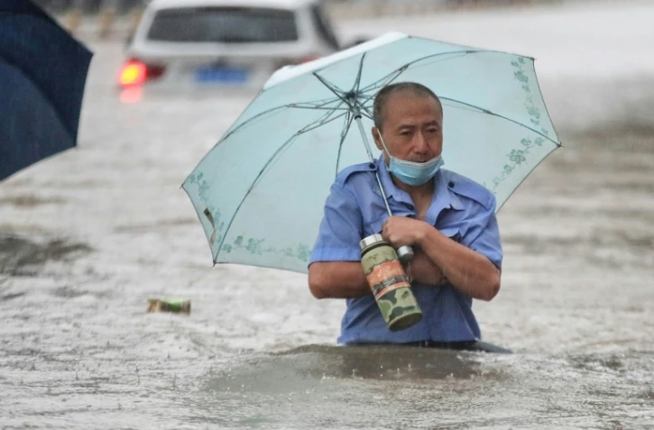 Un homme avance dans une rue inondée de Zhengzhou, placée en alerte rouge après des orages violents qui se sont abattus sur cette métropole du centre de la Chine, le 20 juillet 2021