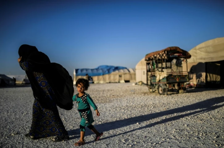 Un Syrienne et son enfant, qui ont fui Raqa et sa région, marchent dans un camp de déplacés à Aïn Issa en Syrie, le 11 juillet 2017