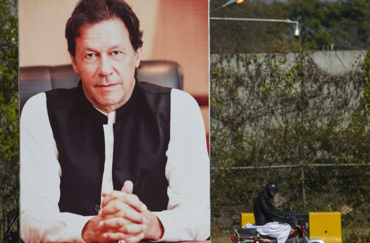 Un homme passe à vélo devant un portrait géant du Premier ministre pakistanais Imran Khan, le 19 février 2019 à Islamabad