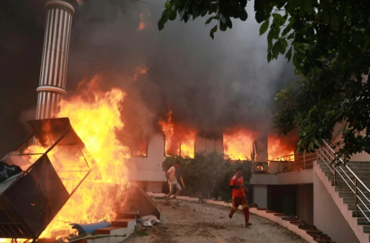 Des manifestants sortent en courant des bureaux du Congrès népalais en flammes, le 9 septembre 2025 à Katmandou