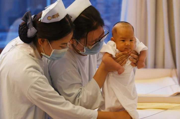 Des infirmières chinoises prennent soin d'un bébé pendant que sa mère se repose, au centre Xiyuege ("Foyer du mois de la chance") à Pékin, le 13 décembre 2016