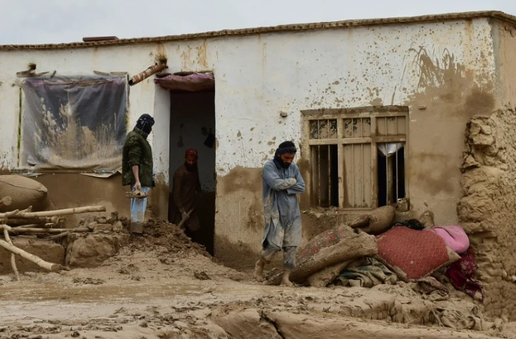 Des Afghans devant une maison ravagée par les crues subites qui ont touché le nord-est de l'Afghanistan, le 11 mai 2024 à Laqiha, dans la province de Baghlan