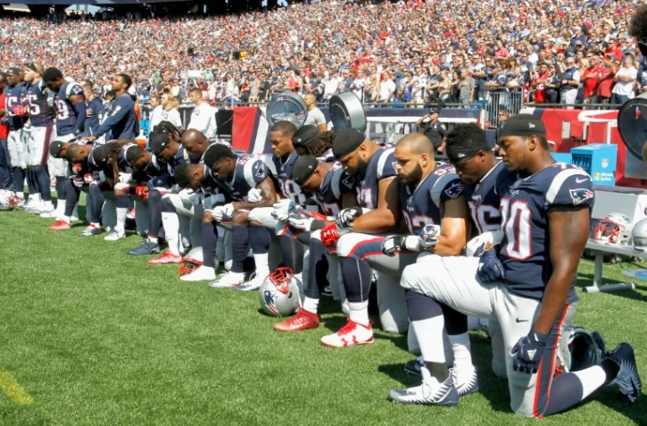 Des joueurs des New England Patriots, agenouillés au bord du terrain quelques heures après que Donald Trump a proposé de boycotter les équipes dont les joueurs "manquent de respect" à l'Amérique, le 24 septembre 2017 à Foxboro