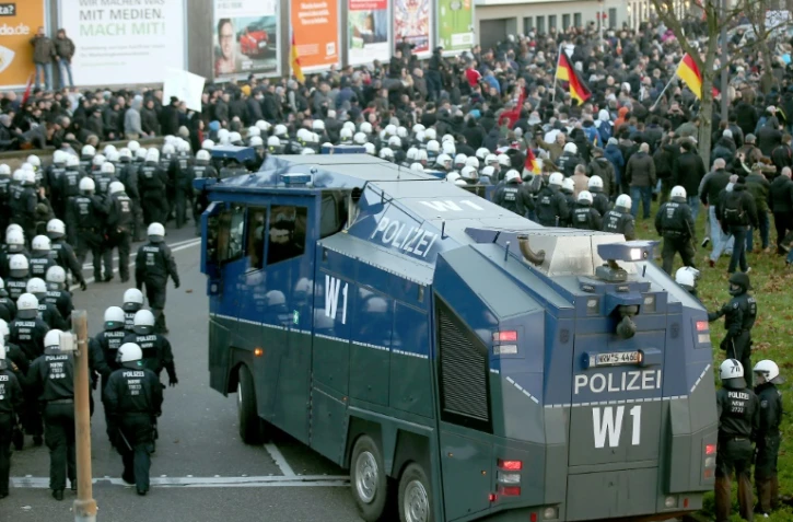 Des policiers marchent près d'un canon à eau pour disperser la manifestation de Pegida à Cologne le 9 janvier 2016