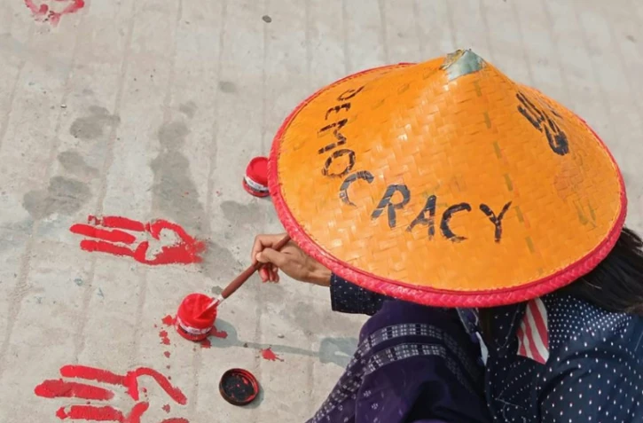 Photo prise et diffusée le 14 avril 2021 par une source anonyme via Facebook d'une manifestante à Shwebo dessinant sur le sol le salut à trois doigts avec de la peinture rouge en signe d'opposition au coup d'Etat militaire en Birmanie