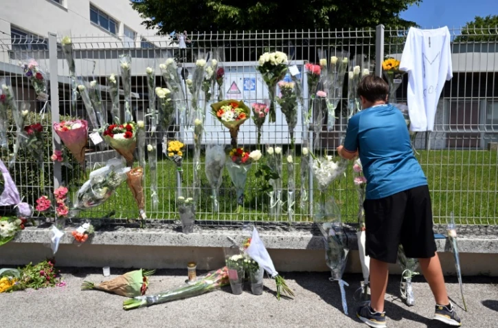 Un élève accroche des fleurs sur les grilles du collège Françoise-Dolto à Nogent, en Haute-Marne, au lendemain du meurtre d'une surveillante, le 11 juin 2025