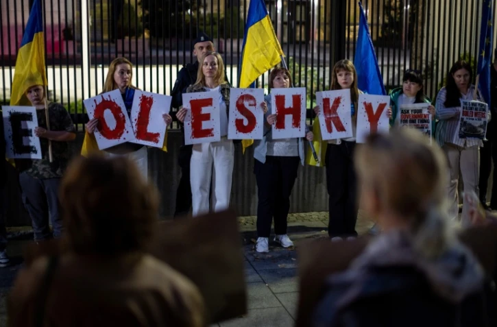 Des membres de la diaspora ukrainienne tiennent des pancartes formant le nom "Oleshky" (Olechky) devant l'ambassade américaine à Varsovie, le 6 octobre 2026