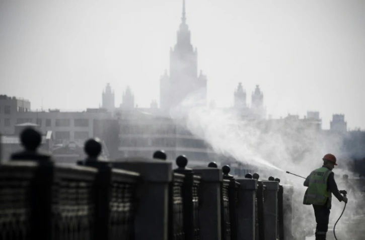Un agent municipal désinfecte les bords des quais à Moscou, devant l'université d'Etat, le 28 mars 2020