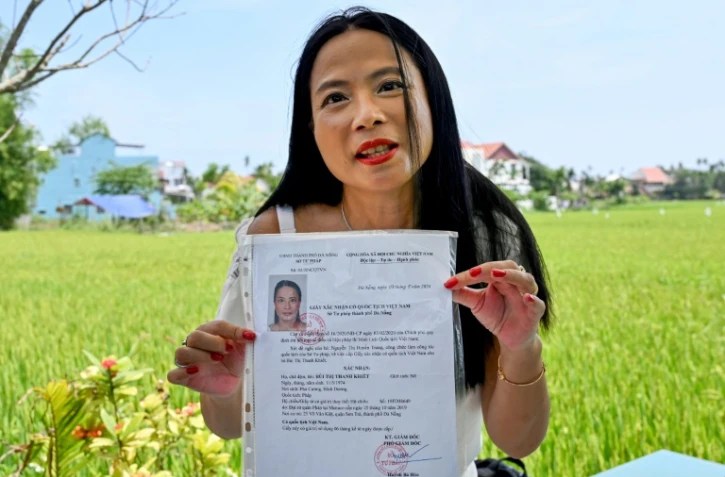 Odile Dussart, évacuée de Saïgon alors qu'elle n'était qu'un bébé de 11 mois, quelques semaines avant la fin de la guerre du Vietnam il y a 50 ans, montre son certificat de nationalité vietnamienne dans sa nouvelle maison à Hoi An, le 12 avril 2025