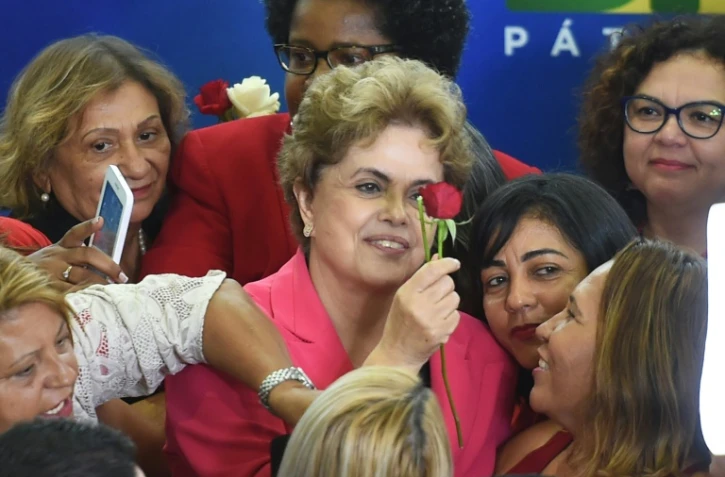 La présidente brésilienne Dilma Rousseff reçoit une rose lors d'une rencontre intitulée "Des femmes en défense de la démocratie" à Brasilia le 7 avril 2016