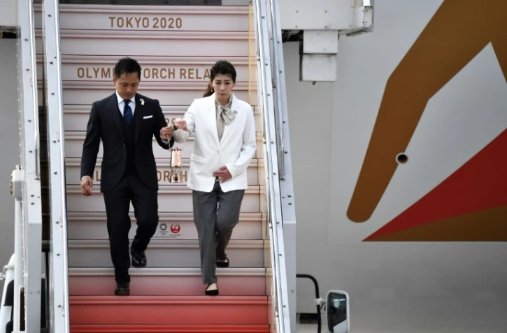 Les anciens champions olympiques Tadahiro Nomura (gauche) et Saori Yoshida (C) amènent la flamme olympique à la base militaire de Matsushima le 20 mars 2020