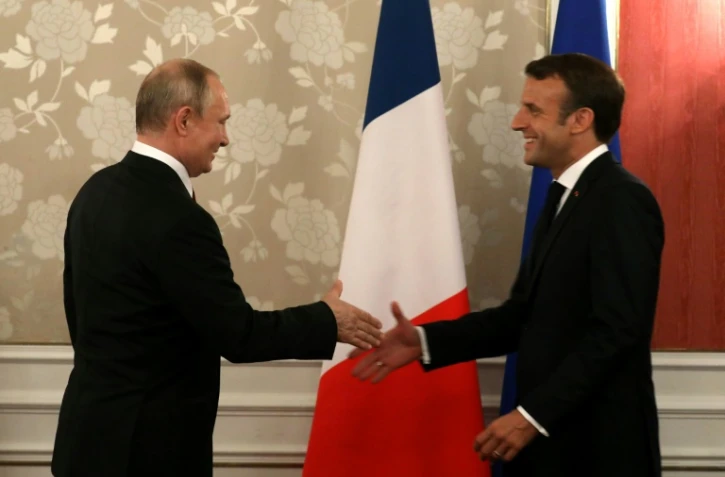 Le président français Emmanuel Macron (D) serre la main de son homologue russe Vladimir Poutine, le 28 juin 2019 lors du sommet du G20 à Osaka, dans le sud du Japon