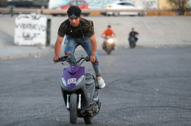 De jeunes Irakiens effectuent des cascades avec leurs scooters pour se divertir, à Bagdad le 6 août 2021