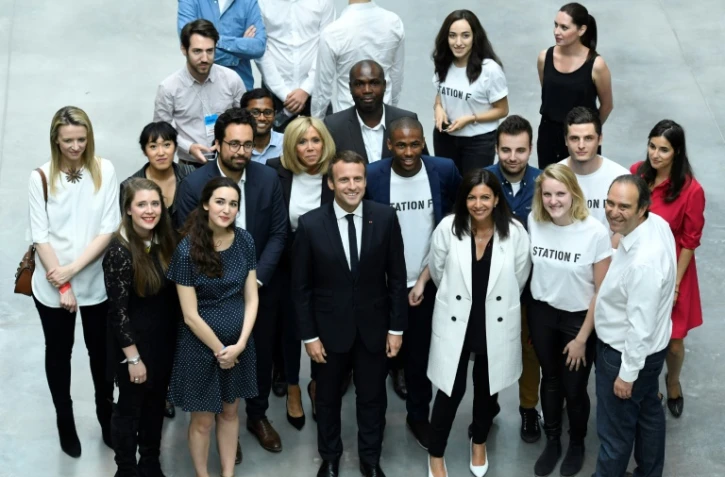 Emmanuel Macron (C), sa femme Brigitte Macron (2e rang, 4e G), le fondateur du groupe de télécoms Iliad (Free), Xavier Niel (bas, D), sa femme Delphine Arnault directrice générale adjointe de Louis Vuitton (2e rang, G), la maire de Paris Anne Hidalgo (bas, 3e D) et le secrétaire d'État français au Numérique Mounir Mahjoubi (2e rans, 3e G), à la Station F, installée dans la Halle Freyssinet à Paris, le 29 juin 2017 