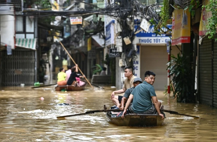 Des habitants se déplacent sur des embarcations après des inondations provoquées par le passage du typhon Yagi,  à Hanoi le 12 septembre.

