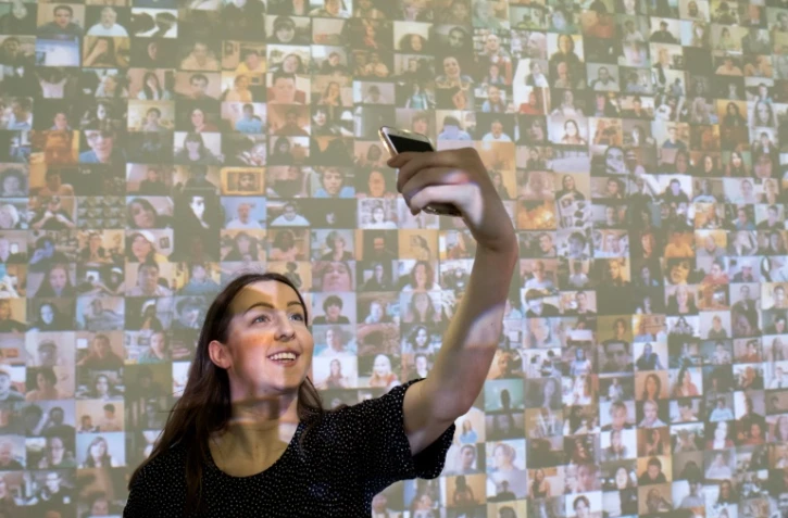 Une selfie sur fond de l'installation "Hello World!" de Christopher Baker dans le cadre de l'exposition "From Selfie to Self-Expression" à Londres, le 30 mars 2017
