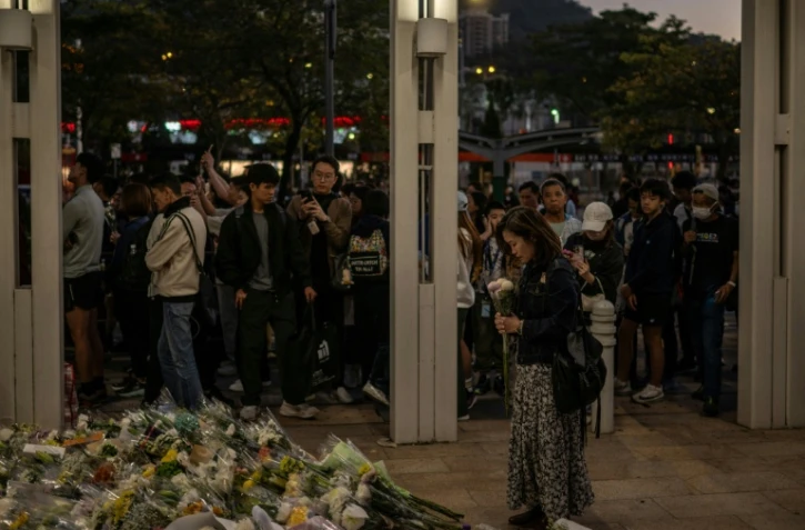 Des habitants de Hong Kong déposent des fleurs devant un complexe résidentiel ravagé par un incendie, le 29 novembre 2025