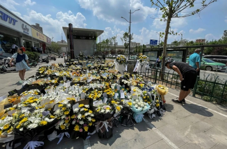 Un homme dépose des fleurs devant une station de métro en mémoire des victimes des inondations à Zhengzhou, dans la province centrale chinoise du Henan, le 27 juillet 2021