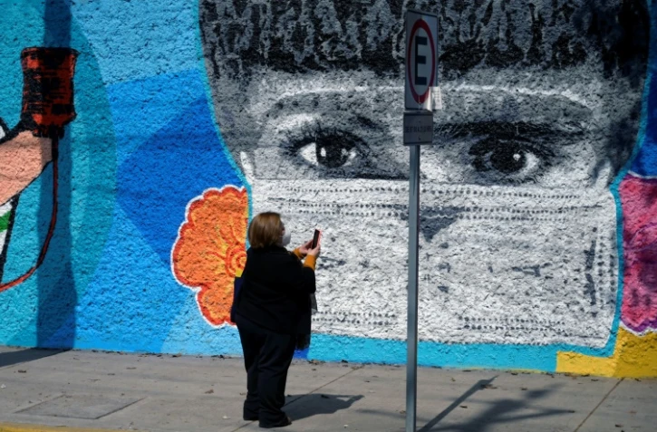 Une femme prend une photo d'une fresque dédiée aux soignants de la crise du Covid-19 à Mexico le 9 décembre 2020