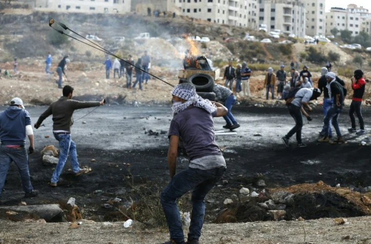 Des Palestiniens lancent des pierres vers des soldats israéliens dans les environs de Ramallah, le 27 octobre 2015