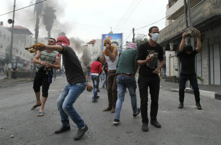 Des Palestiniens jettent des pierres sur des soldats israéliens à Hébron en Cisjordanie, le 26 octobre 2015