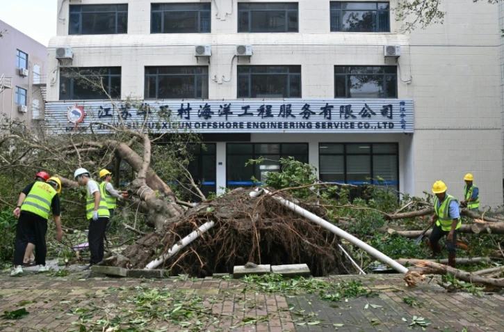 Des ouvriers dégagent un arbre tombé à terre lors du passage du super typhon Ragasa à Yangjiang, dans la province du Guangdong, dans le sud de la Chine, le 25 septembre 2025