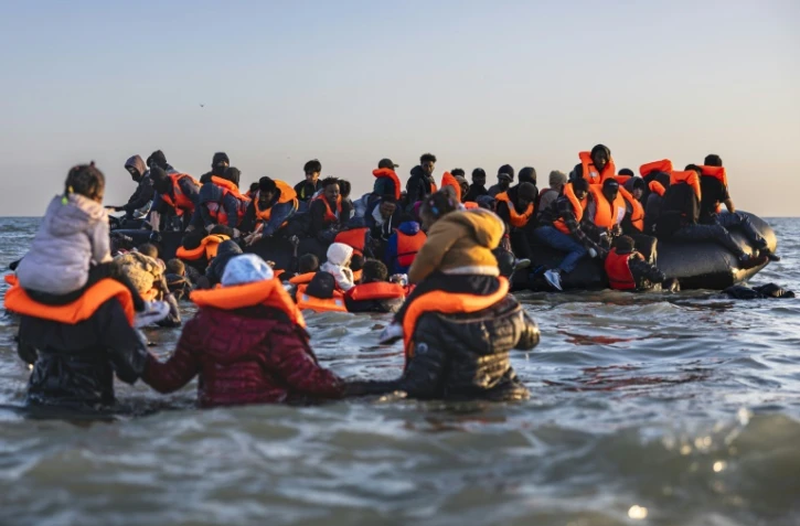 Des migrants avancent dans l'eau pour embarquer sur le bateau d'un passeur et tenter de traverser la Manche au large de la plage de Gravelines, le 16 juin 2025 dans le Nord