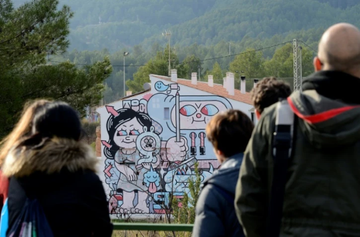 Des visiteurs devant l'une des oeuvres de street art qui ornent les murs du village de Fanzara, le 15 décembre 2016