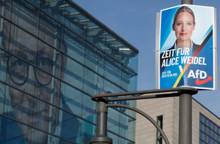 Une affiche électorale de la candidate et co-dirigeante du parti d'extrême droite Alternative pour l'Allemagne (AfD), Alice Weidel (d), devant le siège du parti chrétien-démocrate CDU avec une photo géante de son dirigeant Friedrich Merz sur sa façade, le 24 février 2025 à Berlin