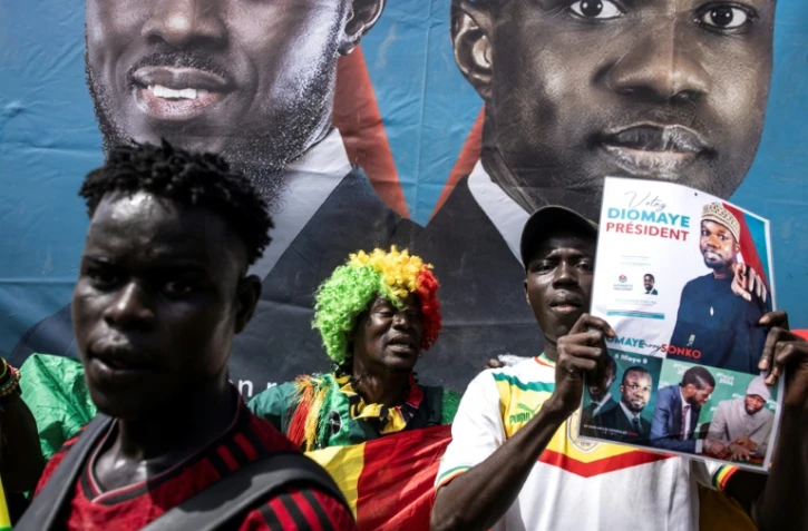 Un partisan brandit une affiche avec le candidat présidentiel sénégalais Bassirou Diomaye Faye et le leader de l'opposition Ousmane Sonko lors d'un rassemblement à Dakar le 10 mars 2024