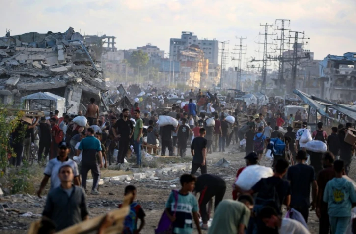 Des Palestiniens marchent le long d'une route de retour d'un point de distribution d'aide de la Fondation humanitaire de Gaza (GHF,) près du camp de réfugiés de Nousseirat, dans le centre de la bande de Gaza, le 25 juin 2025