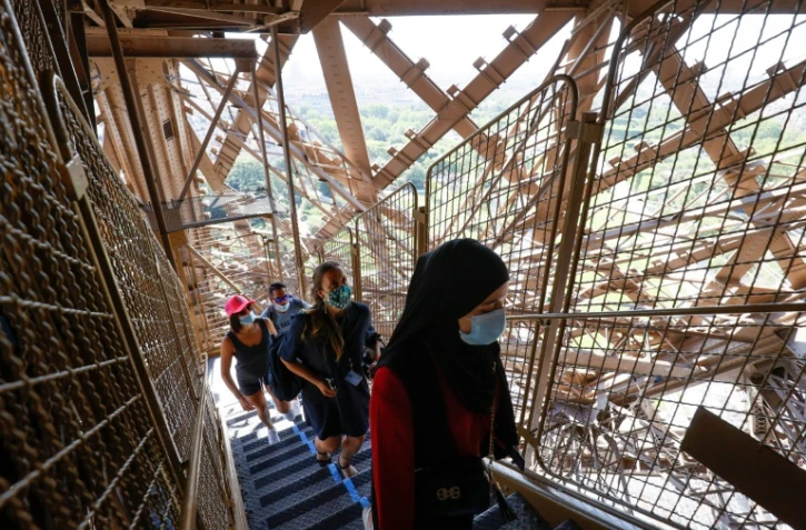 Des visiteurs portant des masques de protection montent les escaliers de la Tour Eiffel, le jour de sa réouverture, le 25 juin 2020 à Paris