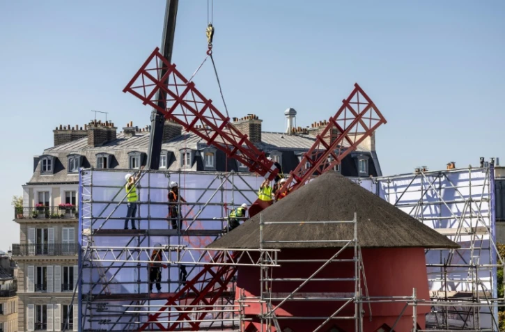 Des ouvriers installent l'une des quatre pales provisoires au sommet du cabaret le Moulin Rouge, après l'effondrement des anciennes ailes, le 24 juin 2024 à Paris