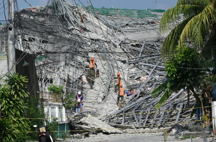 Des militaires accompagnés d'un chien fouillent les décombres d'un immeuble effondré à Angeles City, dans la province de Pampanga, au nord de Manille, le 25 mai 2026 aux Philippines