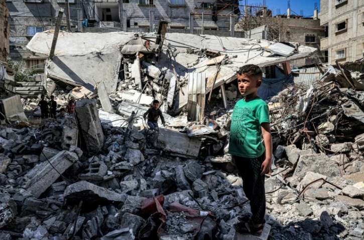 Un enfant se tient parmi les ruines d'un bâtiment effondré, le 9 avril 2024 à Rafah dans la bande de Gaza