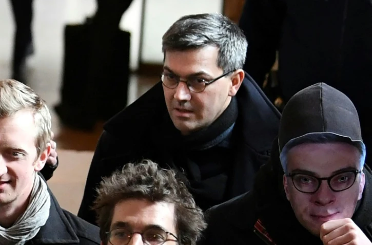 Le chef du groupe dit "de Tarnac" Julien Coupat arrive au procès avec une personne portant le masque du procureur Olivier Christen, le 13 mars 2018
