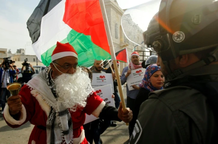 Un manifestant palestinien habillé en père Noël s'oppose à un membre des forces de l'ordre israélienne à Bethléem, en Cisjordanie occupée, le 23 décembre 2017